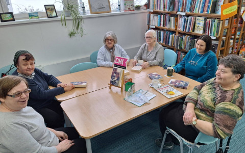 Panie siedzą przy stole i dyskutują o przeczytanej książce