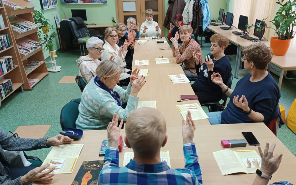 Uczestnicy warsztatów Joga Mudry ćwiczą mudrę wiedzy.