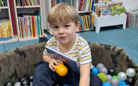 chlopiec pozuje do zdjęcia ze swoim pakietem "Mała Książka, Wielki Człowiek"