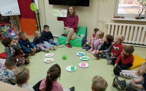 Bibliotekarka pokazuzje ilustracje z książeczki dzieciom