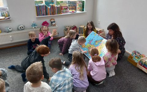 Bibliotekarka pokazuje dzieciom mapę Europy