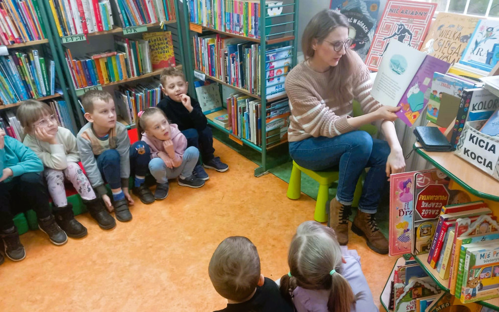 Bibliotekarka czyta przedszkolakom opowiadanie Tove Jansson " Muminek i wiosenna niespodzianka".