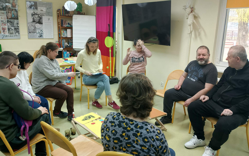 Uczestnicy spotkania siedzą wspólnie z prowadzącą i rozmawiają o wielkanocy