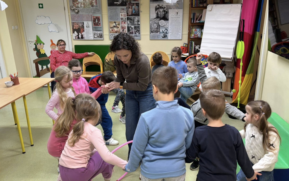 Bibliotekarka przytrzymuje dziecko, które przekład hula-hop.
