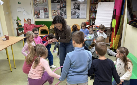 Bibliotekarka przytrzymuje dziecko, które przekład hula-hop.