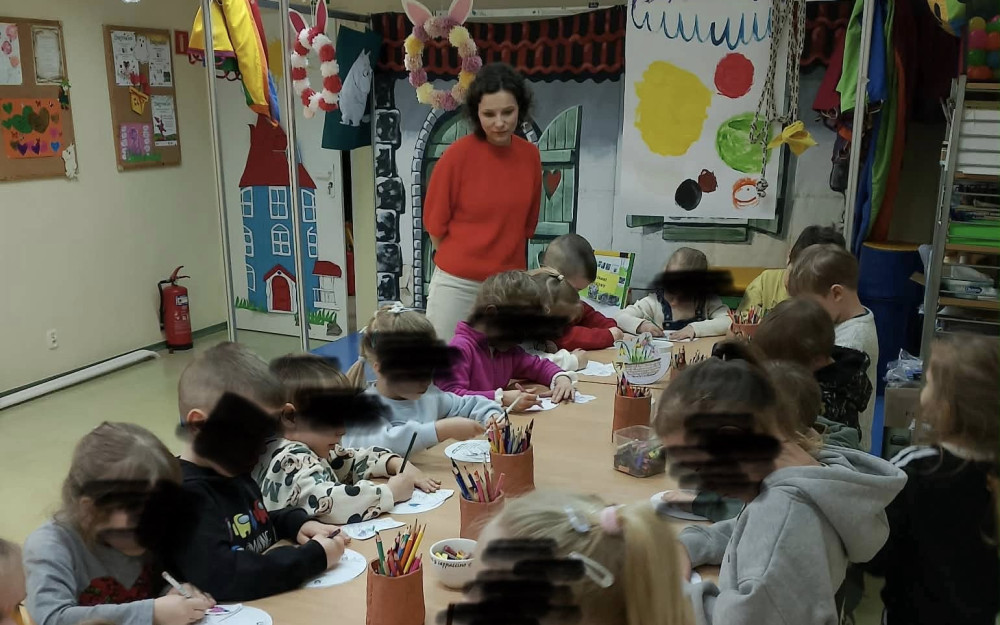 Dzieci stoją przy stolikach i wykonująprace plastyczne