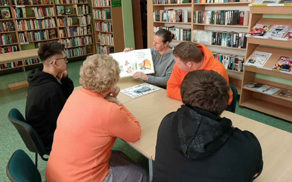 Bibliotekarka pokazuje uczestnikom zajęć książkę O wilku, który wypadł z książki.