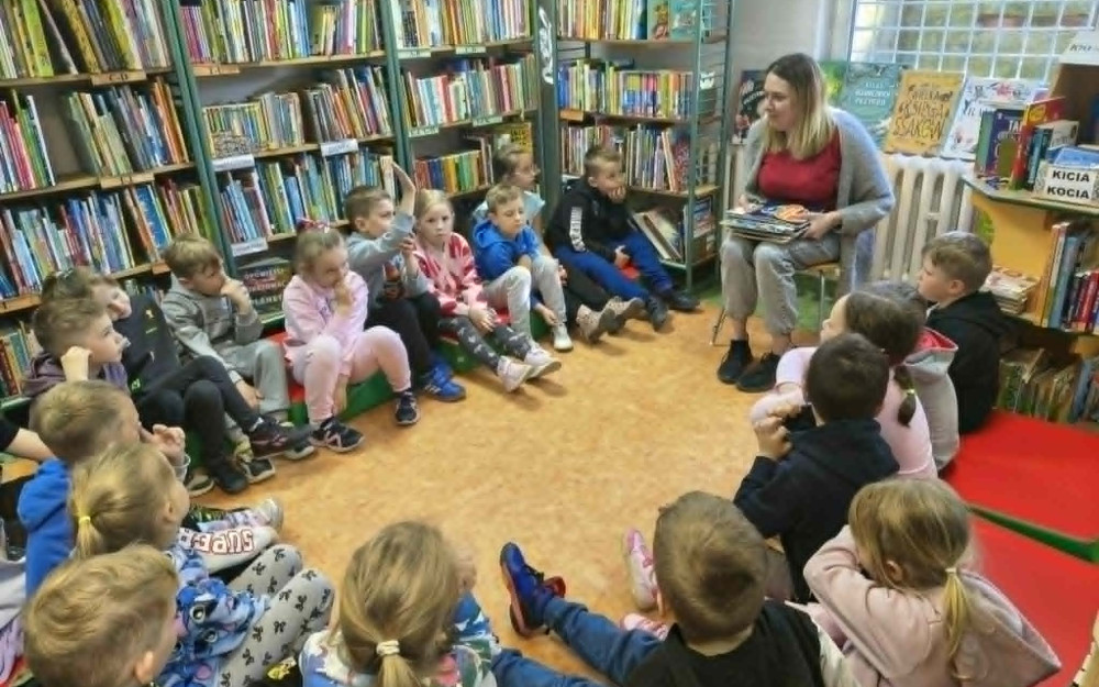 Bibliotekarka pokazuje dzieciom książki.
