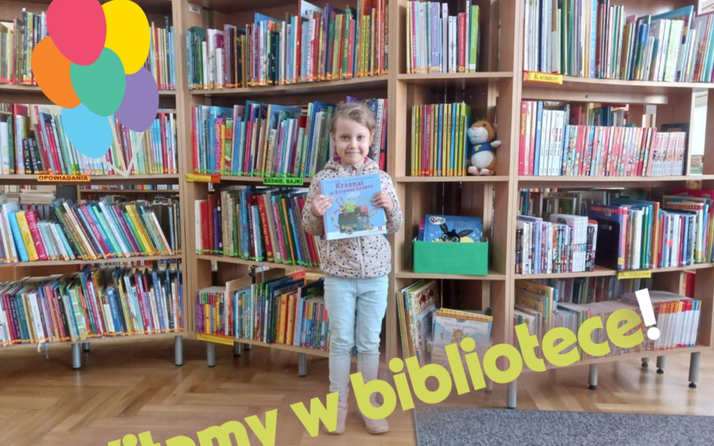 Dziewczynka stoi i w rekach trzyma książkę, w tle książki