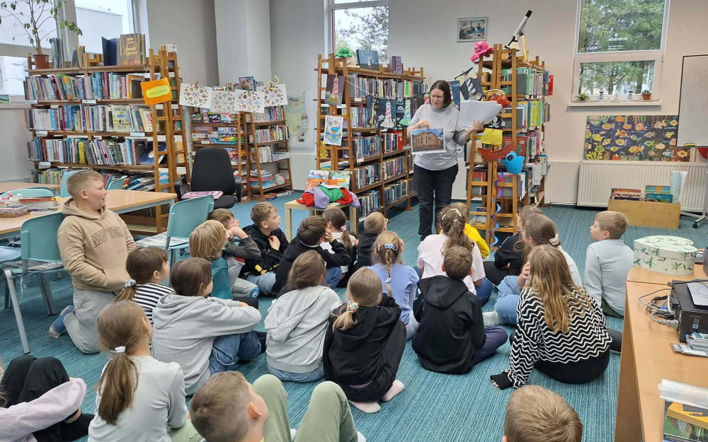 bibliotekarka pokazuje ilustrację Bałtyckiego Teatru w Koszalinie