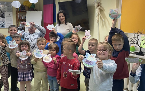 Dzieci stoją i prezentują swoje prace plastyczne
