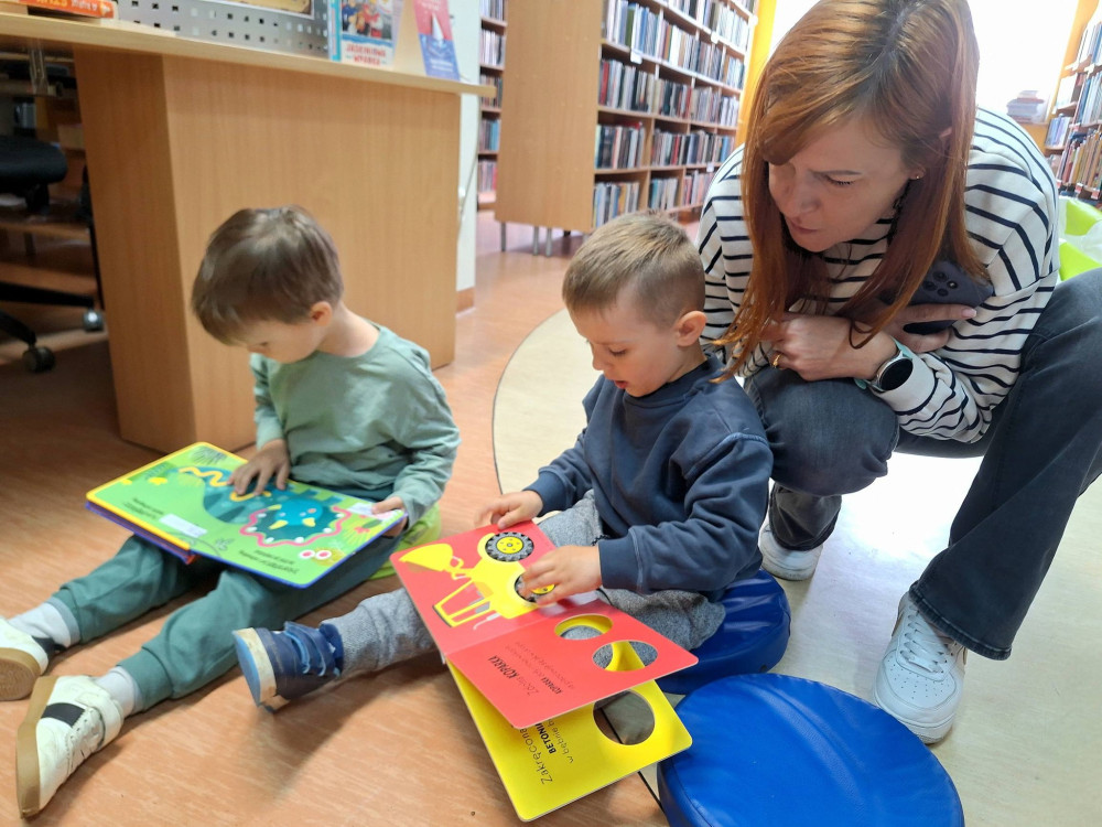 Na zdjęciu przedszkolaki pod opieką nauczycielki, przeglądają najpiękniejsze książeczki w naszej bibliotece