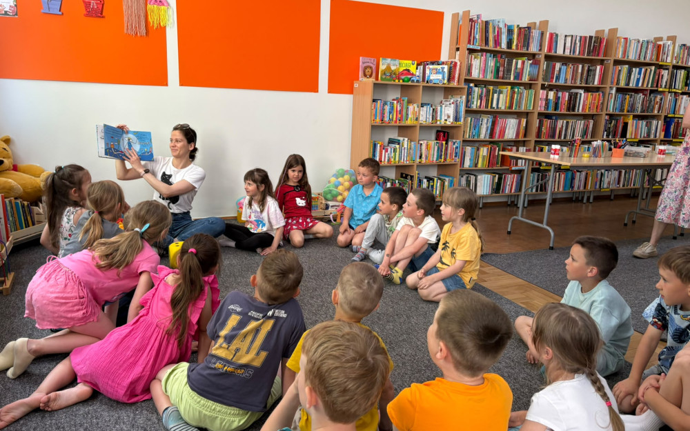Bibliotekarka czyta książkę. dzieci siedzą na dywanie