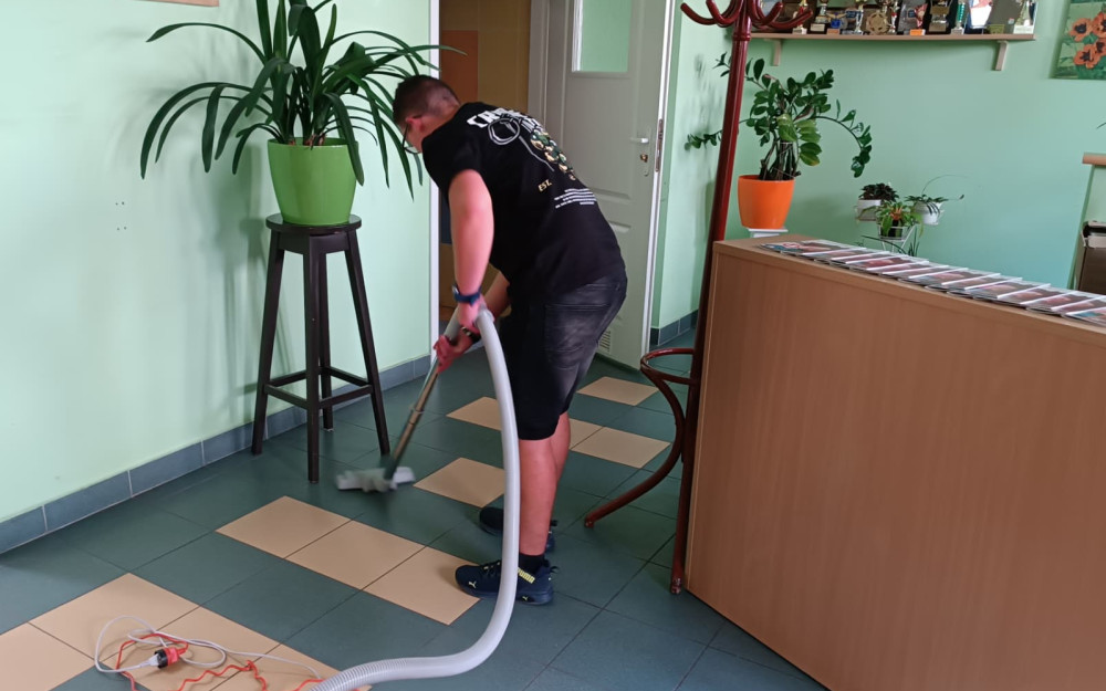 Uczestnik odkurza korytarz biblioteki.