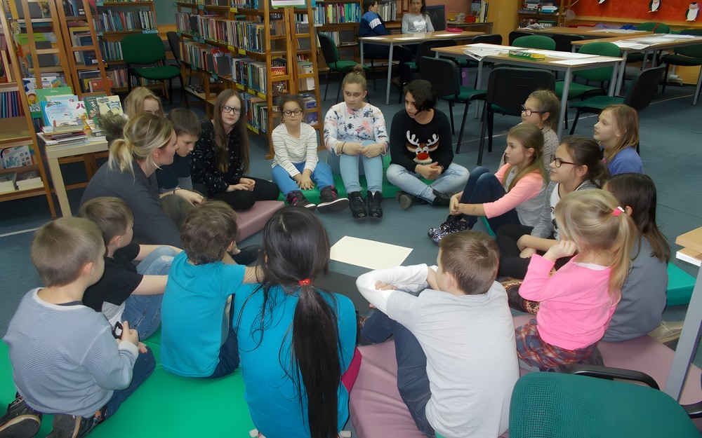 bibliotekarka i dzieci siedzi siedzą na materacach w kole
