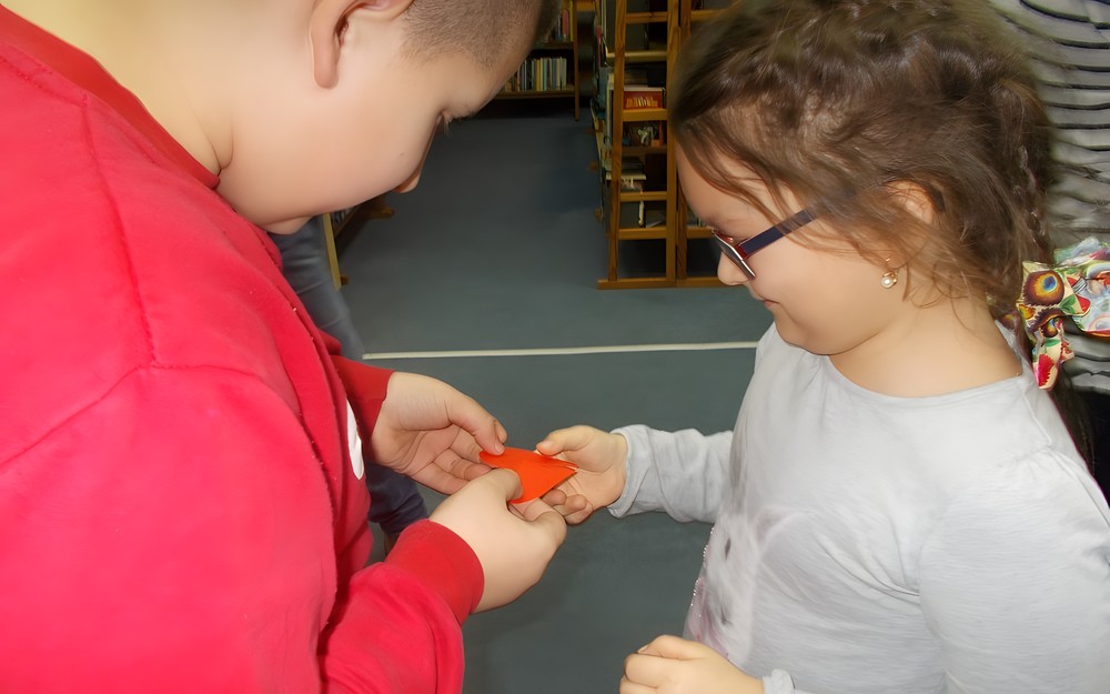 chłopiec i dziewczynka dopasowują połówki serc z papieru