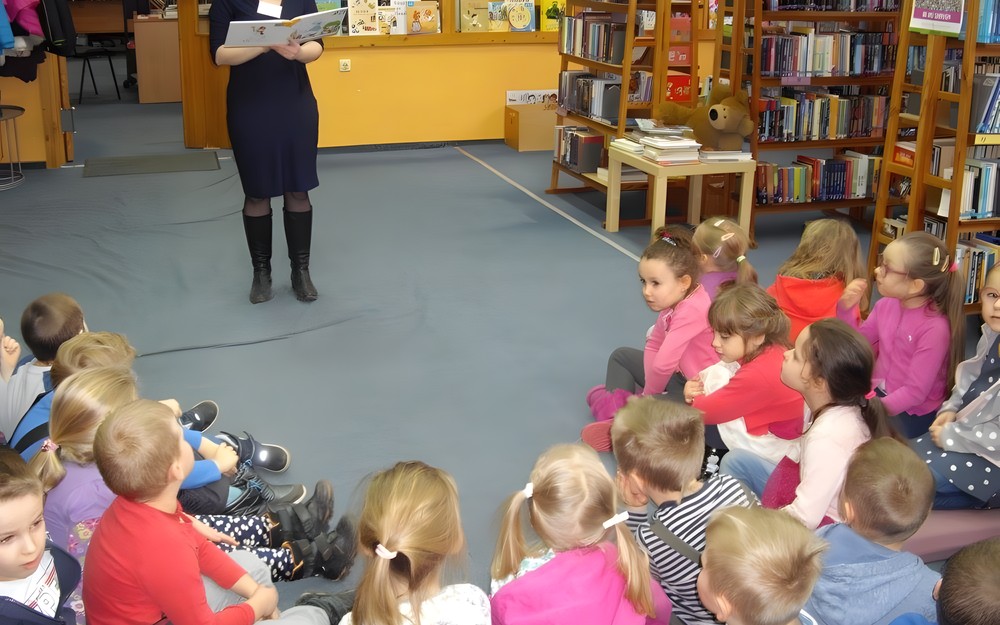 Bibliotekarka czyta książkę dzieciom, siedzącym na materacach