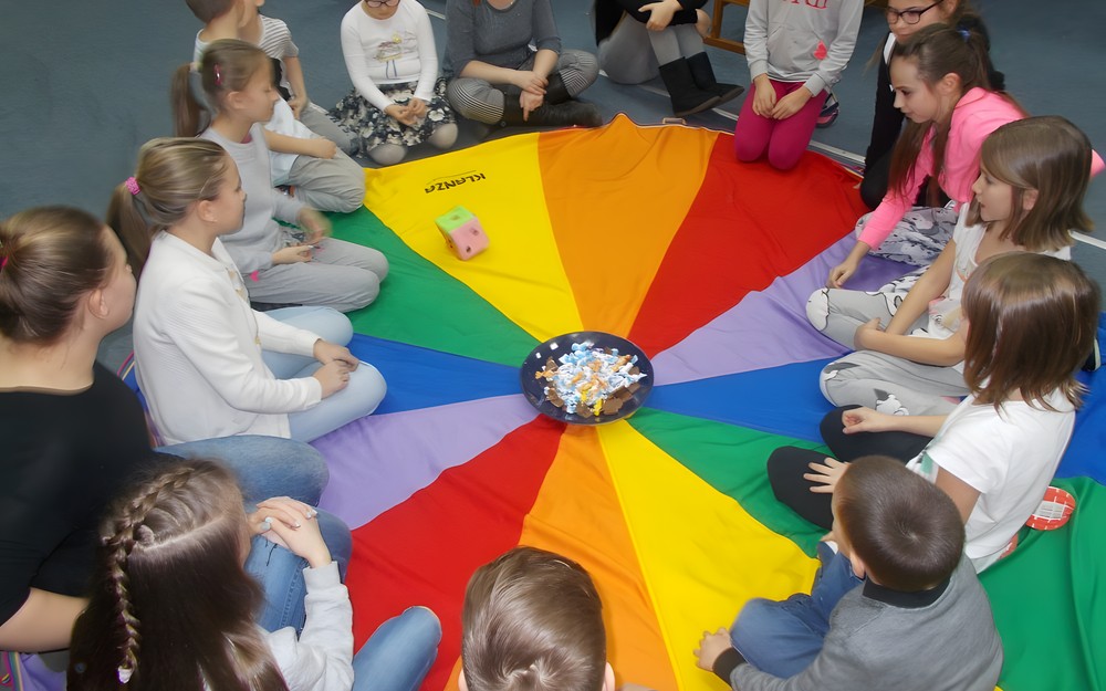 Dzieci z bibliotekarką siedzą na chuście animacyjnej