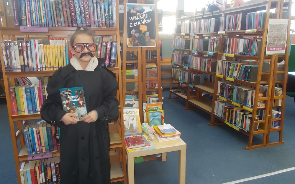 Zdjęcie dziewczynki przebranej za detektywa z książką w ręku