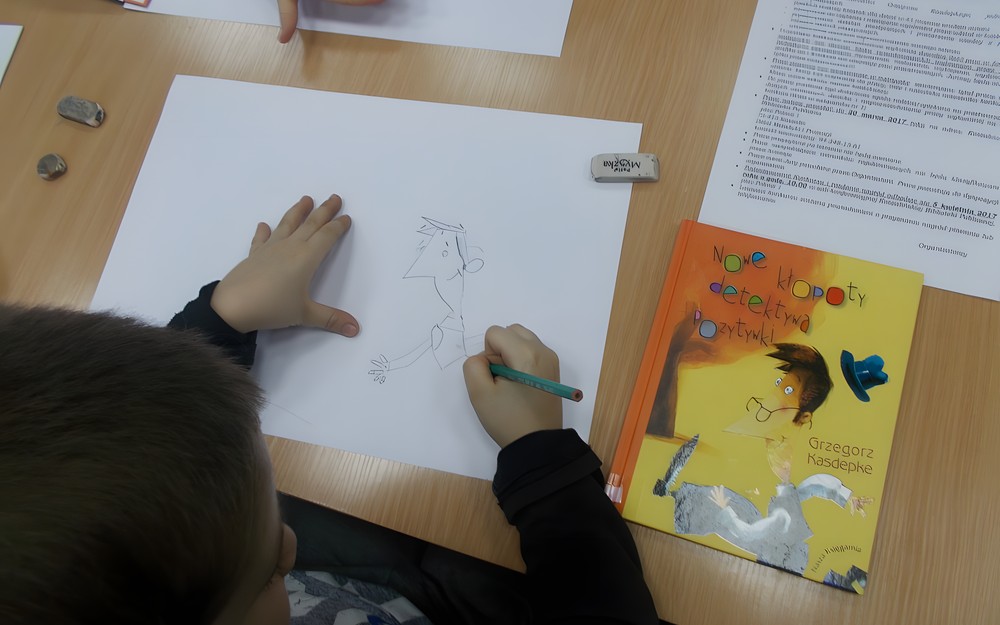 Chłopiec wykonuje pracę plastyczną ołówkiem