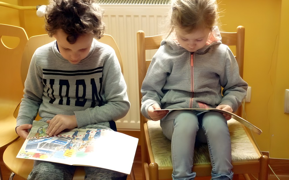 Chłopiec i dziewczynka w wielkim skupieniu oglądają książeczki o zawodach