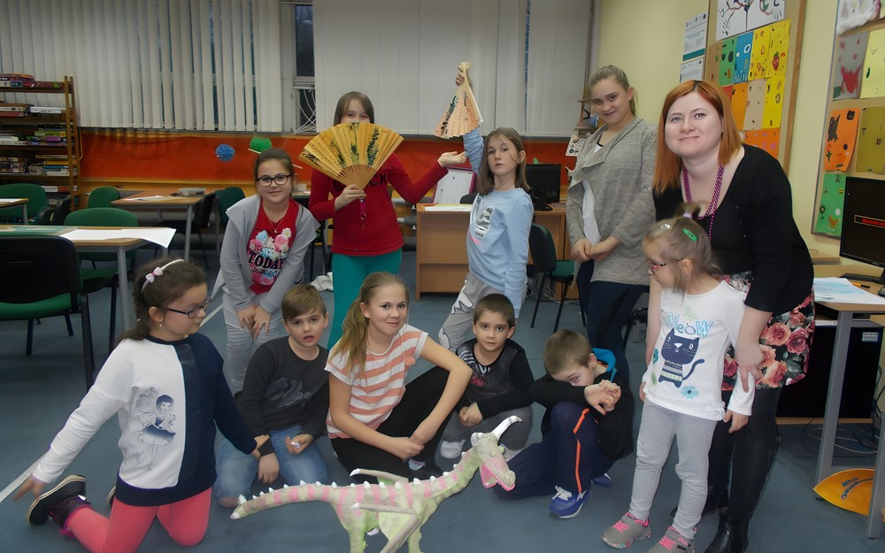 Dzieci z bibliotekarką pozują do wspólnego zdjęcia