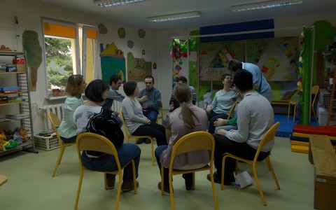 Podopieczni Warsztatów Terapii Zawodowej podczas zabawy. Grupa siedzi na krzesłach ustawionych w krąg.