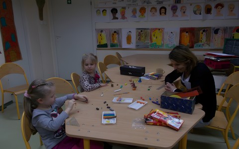 Dzieci siedzą przy stole i tworzą plastelinowe zwierzątka.