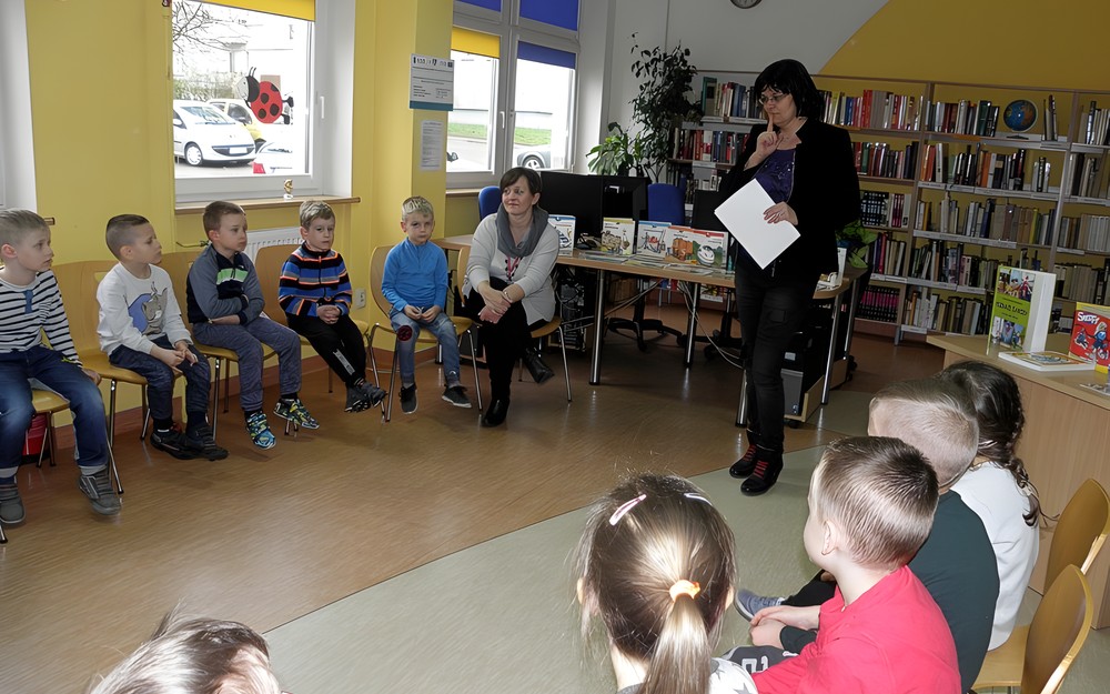 Bibliotekarka wita się z dziećmi i zaraz będzie prezentować książeczki o zawodach