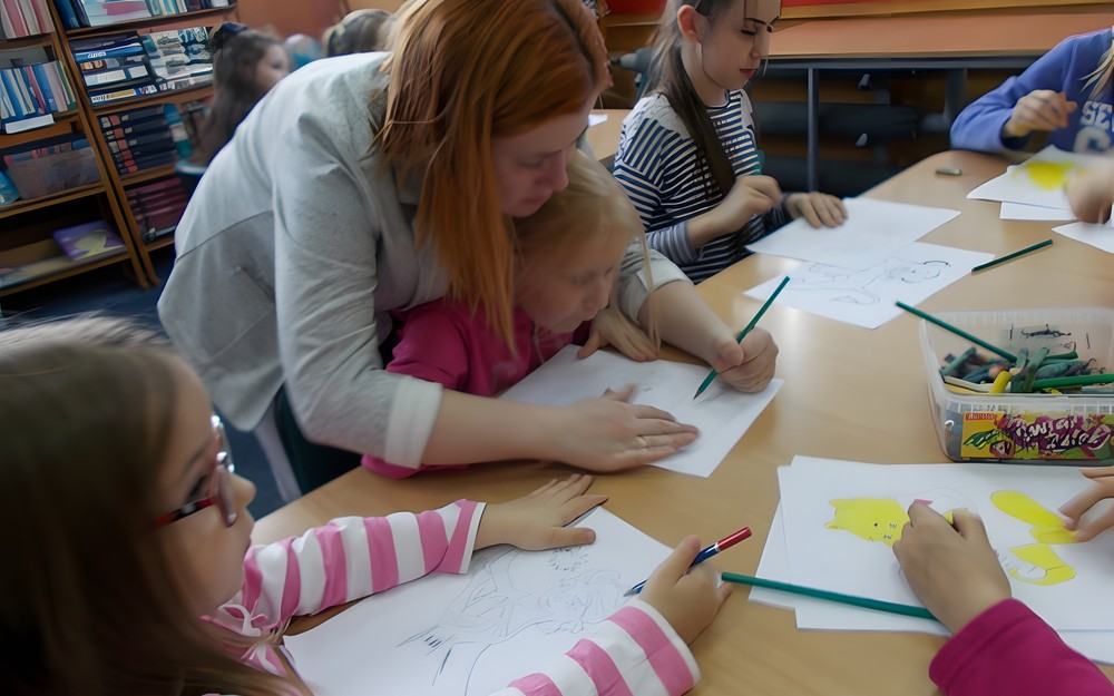 Bibliotekarka pomaga dziecku w rysowaniu pracy
