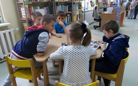 Kilkoro dzieci przy stoliku ogląda ksiązki