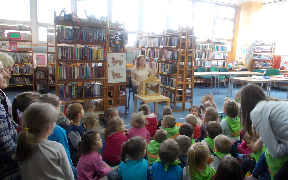 Dzieci siedzą przed bibliotekarką, która pokazuje im teatrzyk