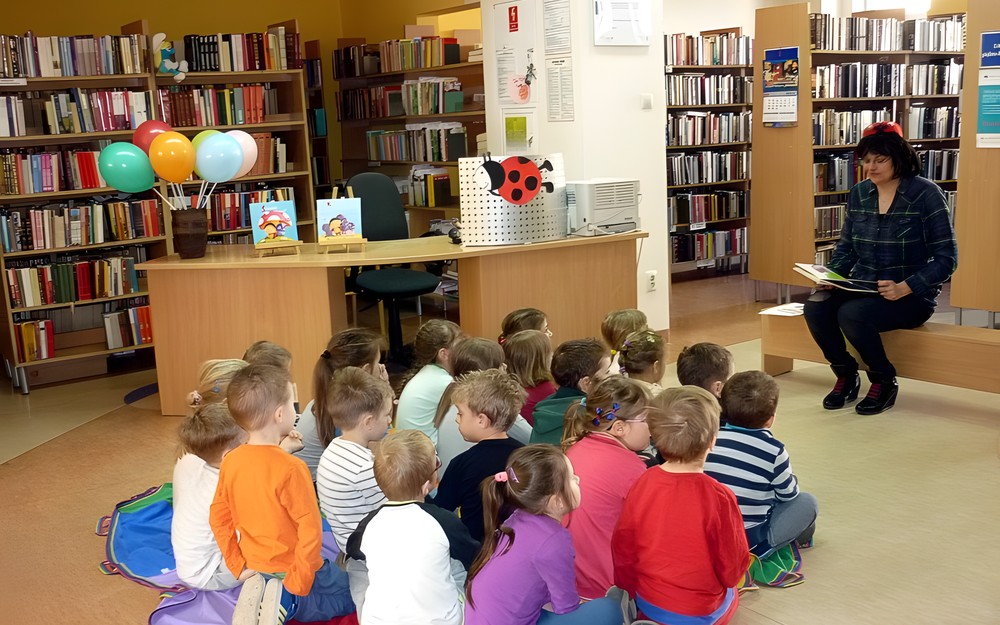Bibliotekarka czyta dzieciom książeczkę pt. BIEDRONKA