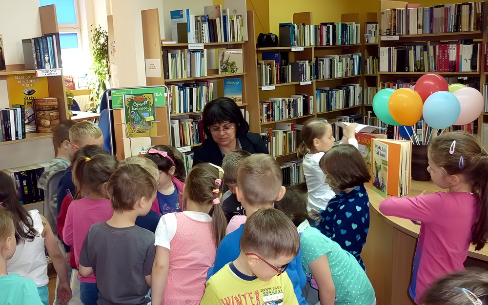 Bibliotekarka w otoczeniu dzieci. Za rozwiązanie BAJKOWYCH ZAGADEK należy się nagroda - cukierek.