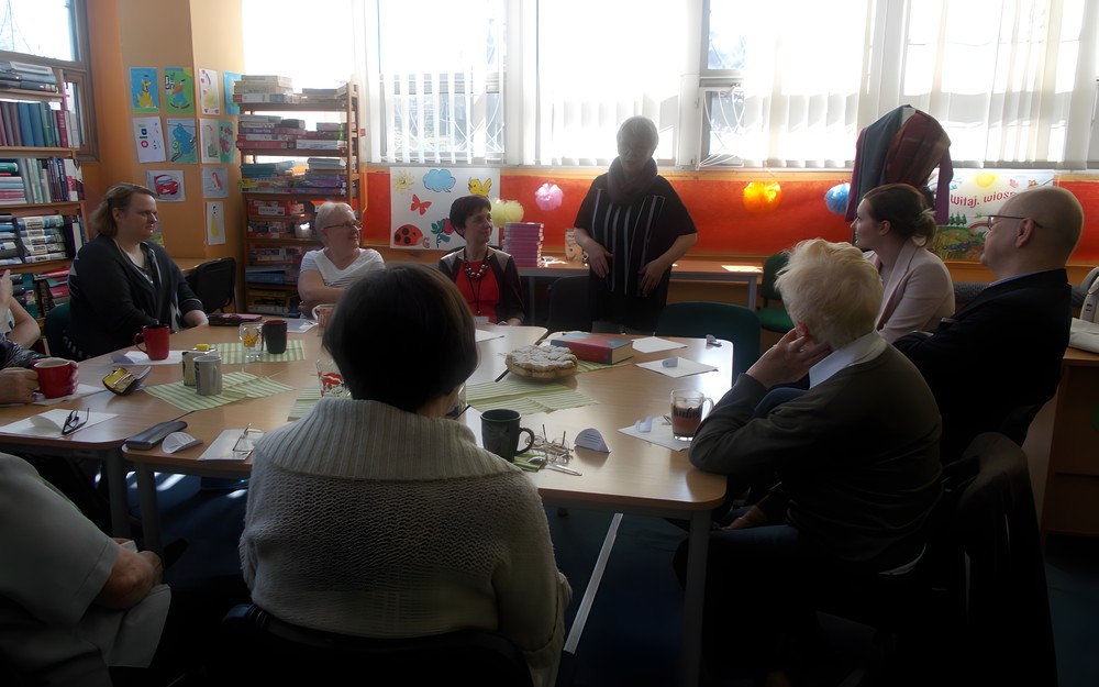 Goście siedzą przy stole, podczas gdy czytelniczka pokazuje im indyjskie sari