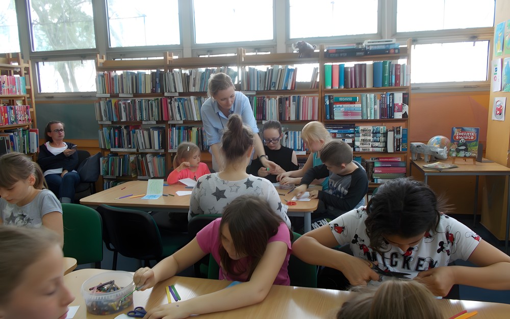 Dzieci przy stolikach wykonują prace plastyczne