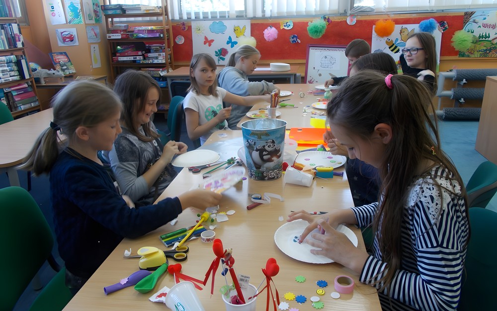 Dzieci przy stole ozdabiają papierowe talerzyki