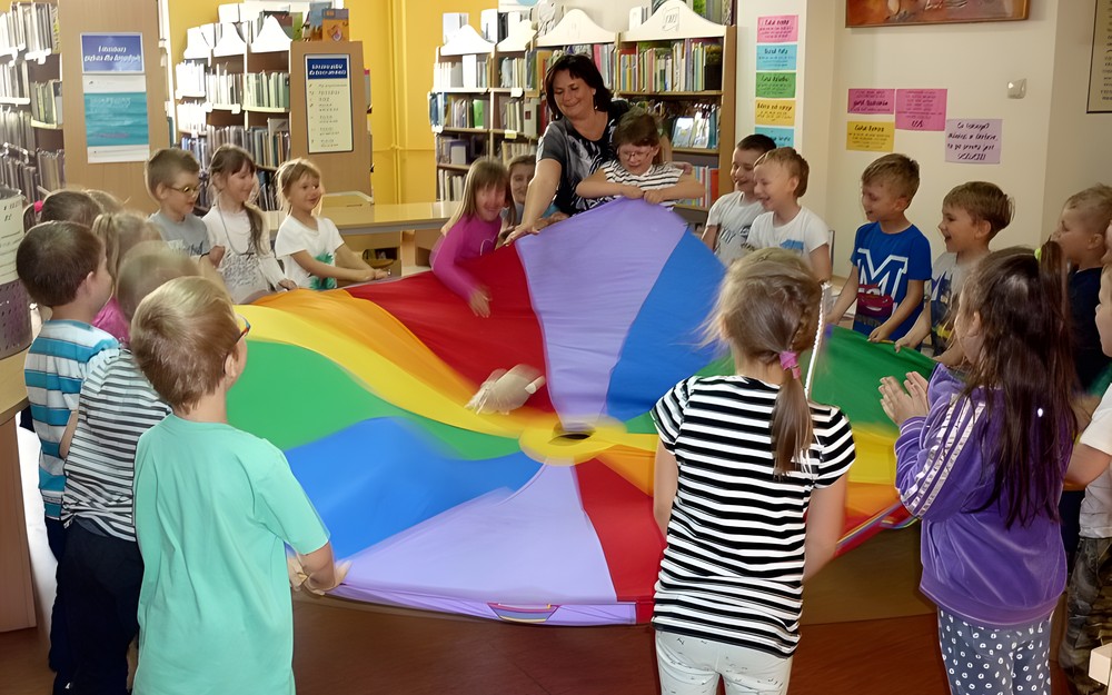 Zabawa z chustą animacyjną. Dzieci podrzucają pluszowego króliczka
