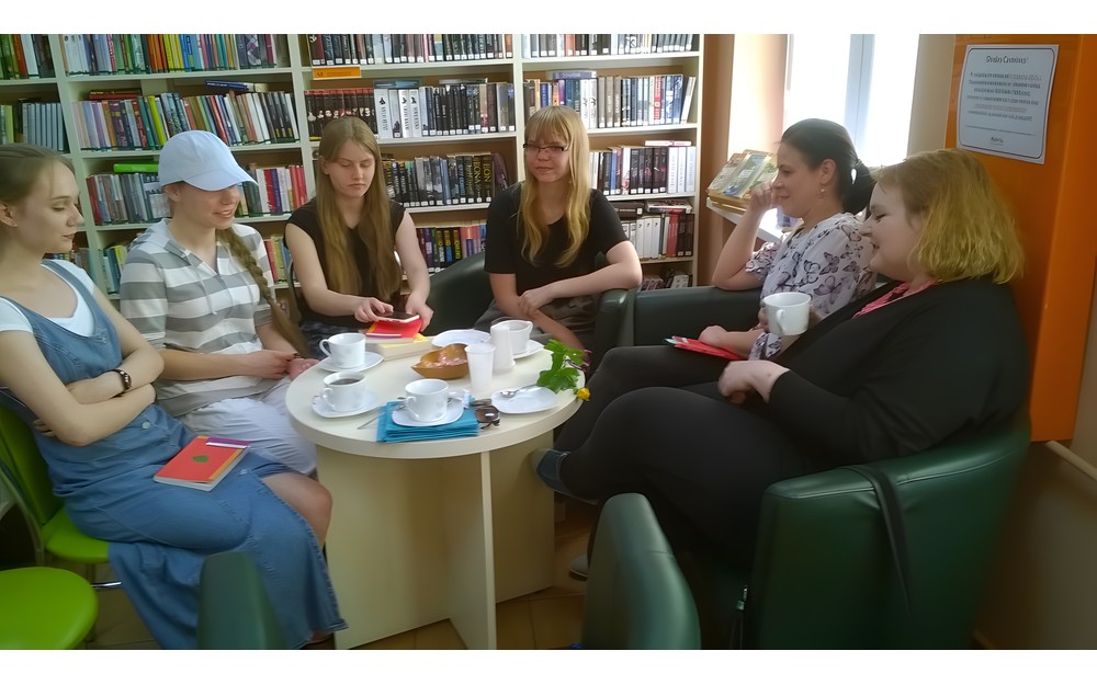 Młodzież siedzi przy stoliku i rozmawia o książce