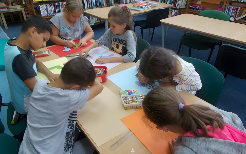 Dzieci siedzą przy stole i malują skarpetki