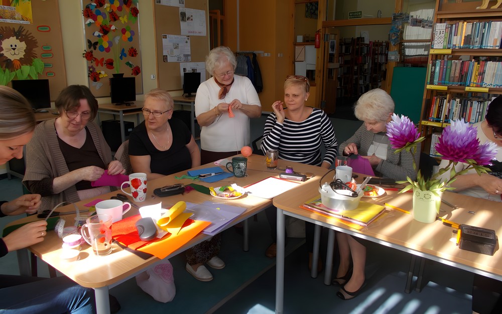 Panie siedzą przy stole wykonując przedmoty z filcu