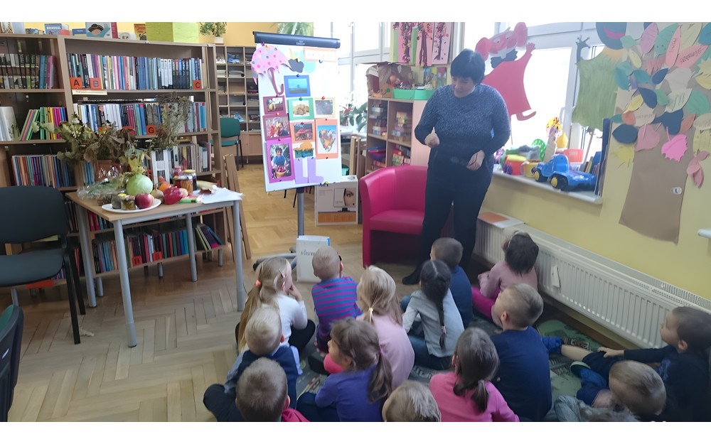 Bibliotekarka opowiada grupie dzieci o jesieni.