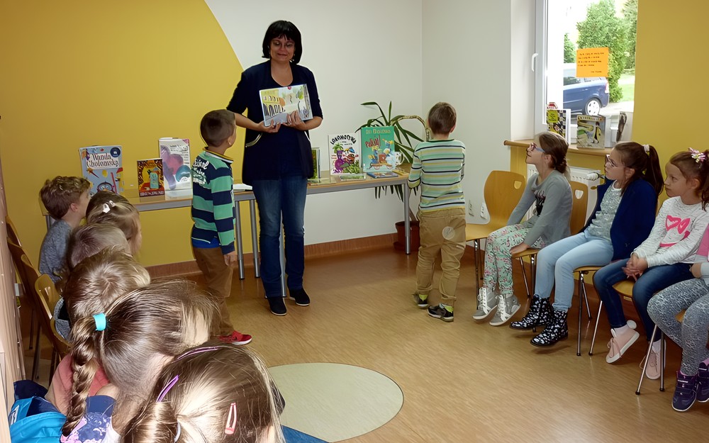Bibliotekarka prezentuje dzieciom książki z wierszykami