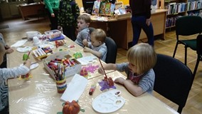 Dzieci siedzą przy stoliku i  malują żówia farbami