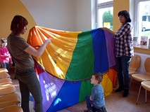 Zabawa z chustą integracyjną. Panie trzymają chustę, a po jej obu stronach ustawiają się dwie drużyn