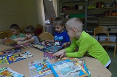 Dzieci wspólnie oglądają czasopisma przy stole