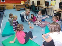 Dzieci siedzą na materacykach i grają wspólnie w grę