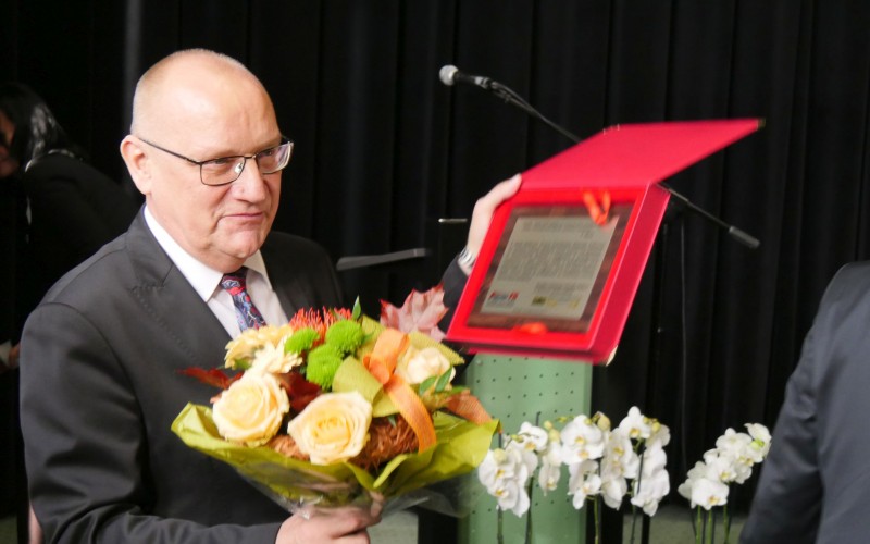Dyrektor KBP Andrzej Ziemiński pokazuje zebranym pamiątkowy list gratulacyjny