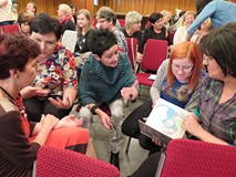 Na zdjęciu grupa bibliotekarek w kręgu przygotowuje prezentację książeczki dla dzieci w czasie warsz