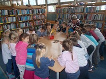 Dzieci stoją przy stole i kolorują ilustracje